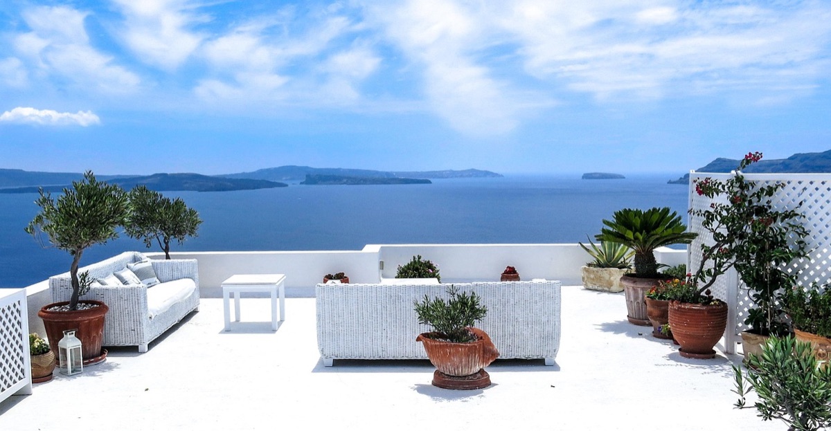 Une photo réaliste d'une vue panoramique du coucher du soleil sur Santorini, avec les reflets du ciel pastel dans la mer.